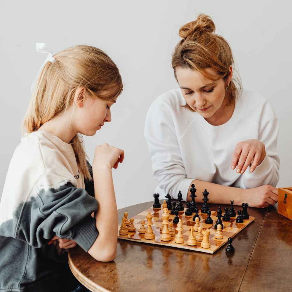 Kid playing chess with mom