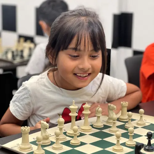 Happy little girl learning chess at CHESS KLUB